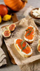 Toasts with red caviar on parchment paper with figs