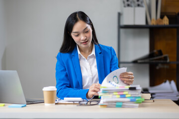 Serious Asian businesswoman working on financial documents and auditing in the office.