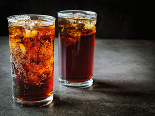 Cola soft drink with ice cubes, soda fizzy drink in Cold two glass on gray background
