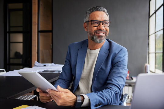 Smiling businessman using tablet while looking out of the window - Powered by Adobe
