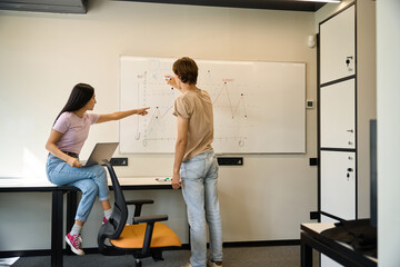 Woman points to charts on whiteboard