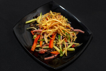 Spicy salad with beef and vegetables on a black background.