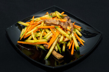 stir-fried vegetables with beef on a black plate on a black background