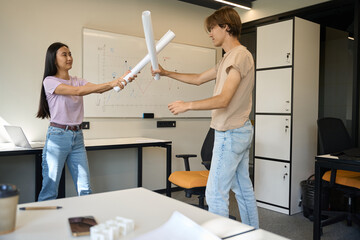 Creative people arranged mock fight with drawings in the office