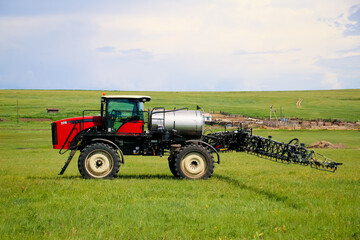 Obraz premium Agricultural machinery on the field. Tractor with a sprayer.