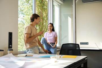 Colleagues chat in a democratic atmosphere by a large window