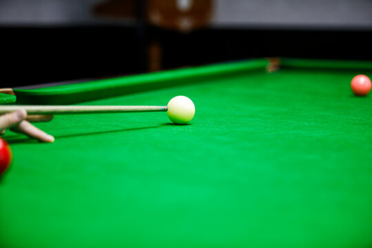 A close-up shot of a snooker player aiming at the cue ball on a green table. A game of precision, focus, and skill in action.