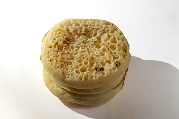 Stack of crumpet, a small griddle bread made from batter of water or milk, yerast and flour. Copy space.