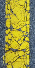 close up cracked yellow line on asphalt surface