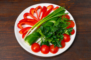 Fresh vegetable platter with red peppers, cucumber, and herbs on a plate Savory vegetable pie served