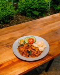 A plate of fried rice on a wooden table with a garden background