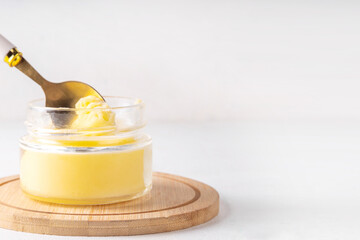 Homemade ghee butter in small glass jar on white kitchen table background, copy space. Melted organic ghee clarified butter, Bio Ayurveda Lactose free high quality animal fat source