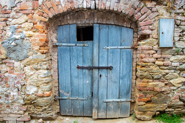 Old wooden door close-up on a background of a wall . Old house exterior

