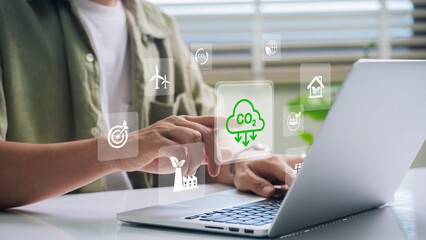 A person interacts with a laptop, touching a holographic CO2 icon, representing carbon emissions management and sustainable technology solutions.