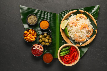Piece of banana leaf with different food, spices and sauce on grey textured table, top view....