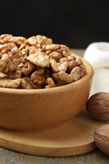 Peeled walnuts in bowl on wooden table, closeup