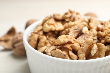 Peeled walnuts in bowl on light table, closeup