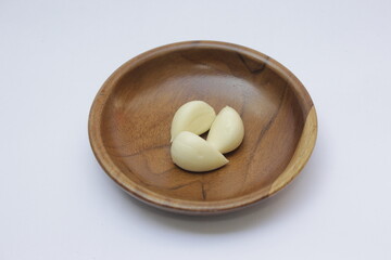 Closeup of Garlic or Allium sativum on wooden plate with a white background