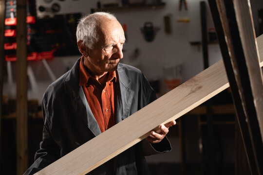 Senior retired carpenter at workplace. Carpenters work. Handyman with wooden plank in hands. woodworker in workshop. skilled occupation, creativity and local artisans.