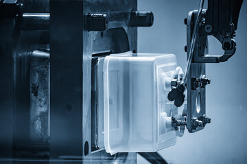 Close up scene material handling process the food container by robotic system from injection...