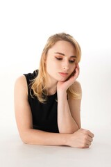 Young woman with thoughtful expression resting her chin on hand in minimalist studio setting