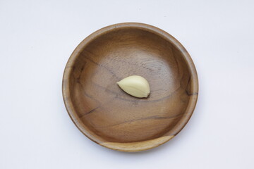 Closeup of a Garlic or Allium sativum on wooden plate with a white background