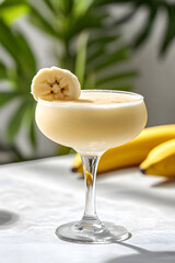 Tropical banana frozen daiquiri served in an elegant glass with fresh bananas in the background