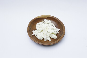 A bunch of White Jasmine or Jasminum sambac flowers in a small wooden bowl on a white background