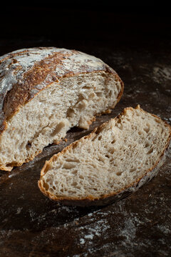 Sourdough bread on a wooden table with flour on dark background