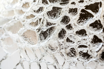 Naklejka premium Macro shot of shattered glass texture, intricate web of cracks forming complex geometric patterns.