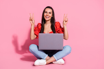Full body portrait of nice young lady sit floor laptop v-sign wear top isolated on pink color background
