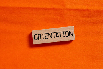Orientation message written on wooden block on orange background. Conceptual orientation symbol....