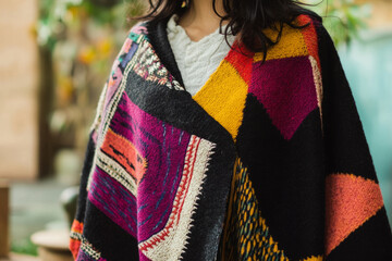 Textured Mexican handwoven poncho, vibrant, with bold geometric patterns woven with thick, cozy threads.