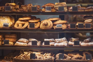 Gordijnen Artisan bakery display filled with freshly baked breads and pastries in a cozy café setting © Cristina