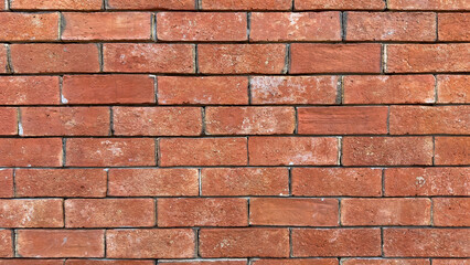 A brick wall with a few cracks and some dirt on it. The wall is red and has a rough texture
