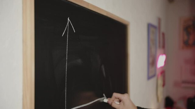 Hand drawing graph on blackboard with chalk