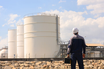 Male chemical engineer doing inspection work at a chemical storage tank on the seaside.