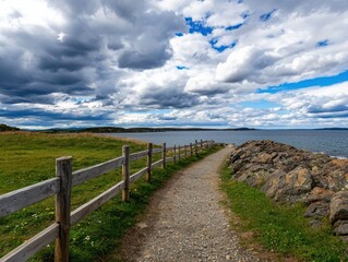 Fototapeta premium A scenic pathway runs alongside a body of water, bordered by a wooden fence, under a sky filled with dramatic clouds.