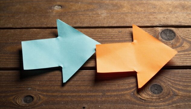 Two arrows made of paper pointing in opposite directions on a wooden table, direction, split