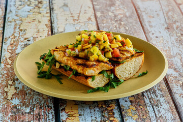 opened faced fresh fish sandwich topped with peach and mango salsa