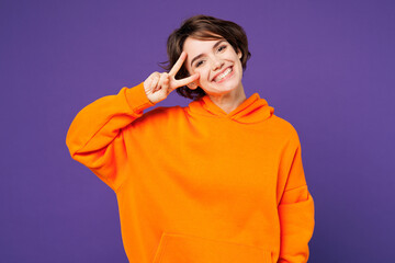 Young smiling happy Caucasian woman she wear orange hoody casual clothes showing cover eye with...