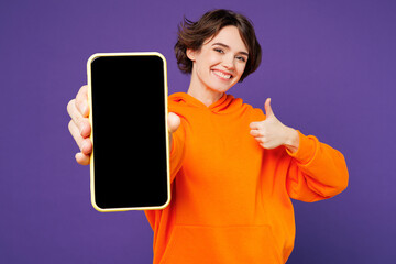 Young happy woman she wear orange hoody casual clothes hold in hand use mobile cell phone with...