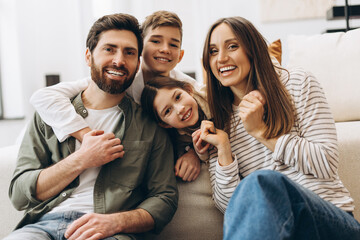 Happy family smiling and embracing on sofa at home