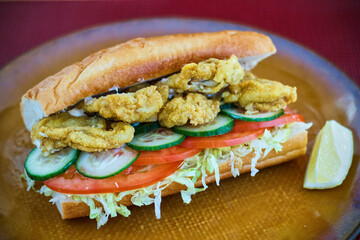 fried oyster po'boy with shredded lettuce, tomato, and cucumber