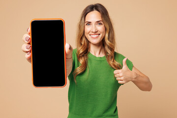 Young woman she wear green t-shirt casual clothes hold in hand using mobile cell phone with blank...