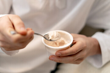Chef holding plastic cup and eating yogurt with spoon