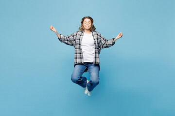 Obraz premium Full body young spiritual woman wears checkered grey shirt casual clothes jump high hold spreading hands in yoga om aum gesture relax meditate try to calm down isolated on plain blue cyan background.