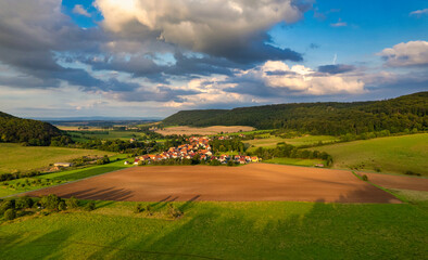 Fototapeta premium Vibrant German Village Nestled in a Valley Surrounded by Lush Greenery and Picturesque Mountains on a Bright Sunny Day