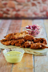 crispy fried chicken tenders served with a mustard dipping sauce on a cutting board