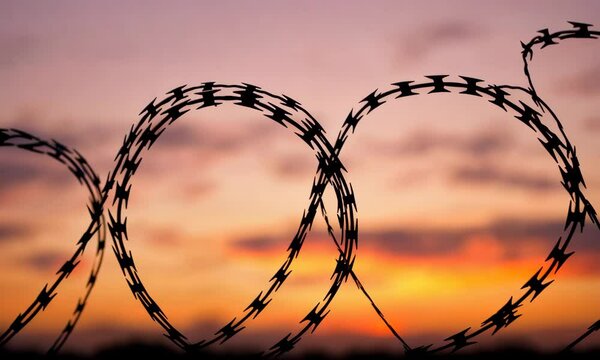 A stark silhouette of barbed wire contrasts against a colorful sunset, symbolizing boundaries and struggles, evoking emotions tied to freedom and barriers in life.